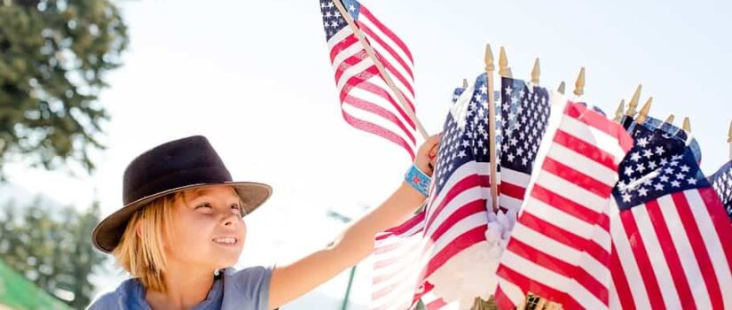 Photo of child reaching for a US flag for post about Independence Day 2023 - Toward a more perfect union